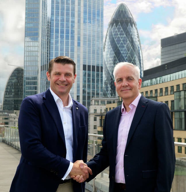 Advania UK CEO, Geoff Kneen, and Servium CEO, Paul Barlow, shaking hanks in front of London buildings