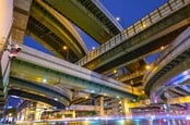 Intersecting above-ground highways (skyways) constructed in intricate pattern, shot from below at night. Photo by Shutterstock 