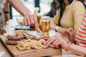 People eating onion rings with other food in a pub setting