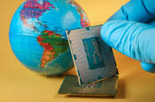 A little globe with some chips stacked by it, held up by a lab worker's gloved hand